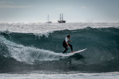 Full length of man surfing in sea against sky