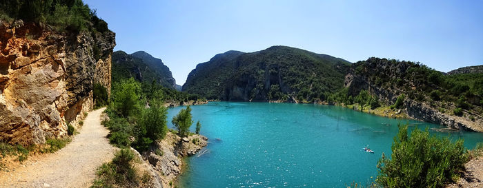 Scenic view of sea and mountains against clear blue sky