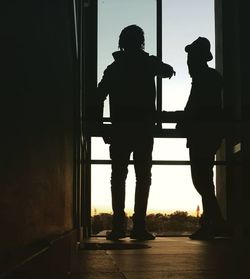 Rear view of silhouette man standing by window