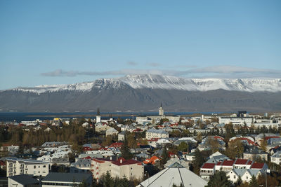 Aerial view of townscape and mountains against sky