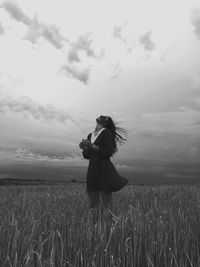 Rear view of woman standing on field against sky