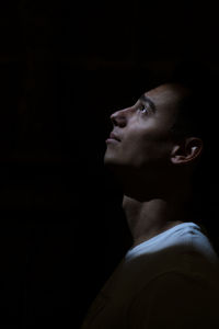 Side view of young man against black background