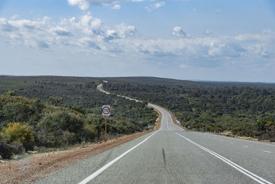 Country road by landscape against sky