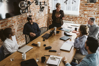 Mature female entrepreneur explaining strategy while sitting on conference table in office