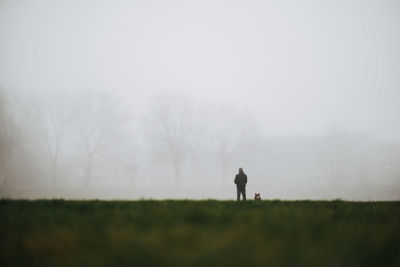 Rear view of man standing on field against sky