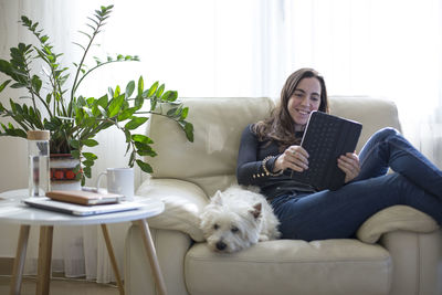 Young woman on the sofa with her dog making a video call