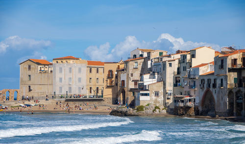 Buildings by sea against sky