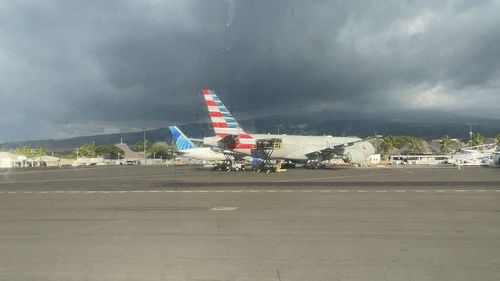 Airplane on airport runway against sky