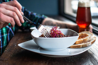 Cropped hands of man having food and drink on table at restaurant