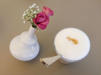 High angle view of latte macchiato by flower vase on table