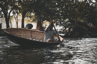 Man fishing in river against trees