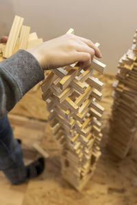 Low section of man building tower of wooden blocks at home