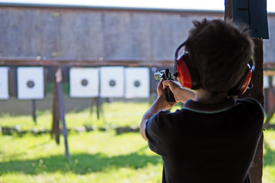 Young boy concentrates while shooting from a revolver at a shooting range