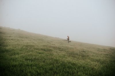 Side view of girl running on grassy field against sky