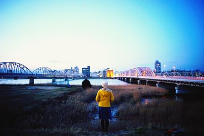 Rear view of woman walking on bridge over river