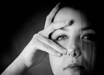 Close-up portrait of young woman against black background