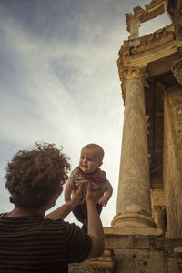 Father holding his baby son in front of historical pillars of roman historica landmark. family trave