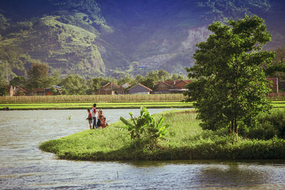 People by lake against trees