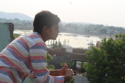 Side view portrait of young man standing against sky