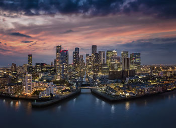 Illuminated buildings in city against sky during sunset