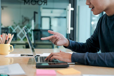 Midsection of businessman pointing on laptop screen while working at table in office 