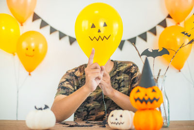 Man covering face with balloon at halloween party