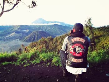 Rear view of man looking at mountains against sky