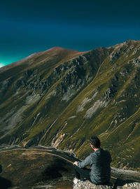 Rear view of woman sitting on mountain