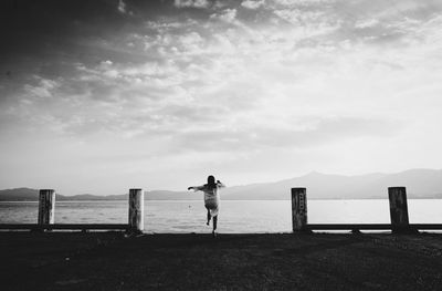 Rear view of woman running towards sea at beach