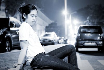 Young woman sitting on road at night