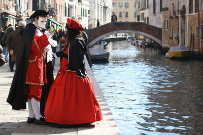 People in canal amidst buildings