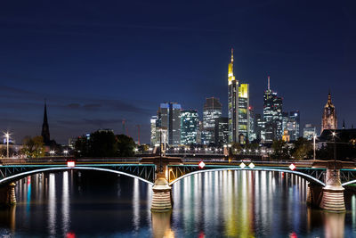 Illuminated bridge over river in city at night