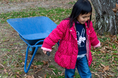High angle view of girl holding wheelbarrow outdoors