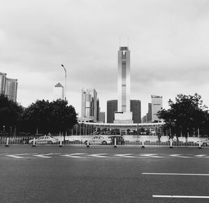 City street by modern buildings against sky