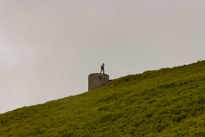 Low angle view of man standing on built structure against sky