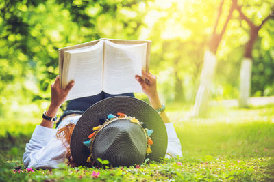 Midsection of woman reading book in park