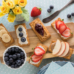 Crackers with different fresh toppings on a wooden board.