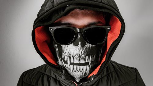 Portrait of man wearing sunglasses against gray background