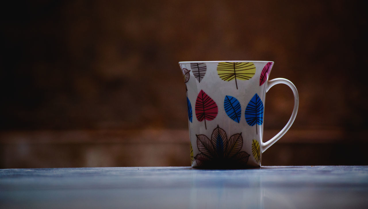 table, cup, indoors, still life, mug, no people, drink, ceramics, refreshment, creativity, wood - material, close-up, selective focus, pattern, design, food and drink, art and craft, coffee, coffee cup, coffee - drink, crockery, floral pattern, tea cup