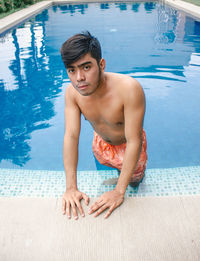 Portrait of shirtless man standing in swimming pool