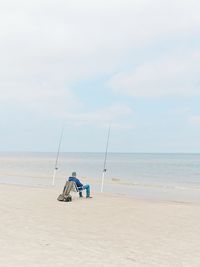 Men fishing at beach against sky