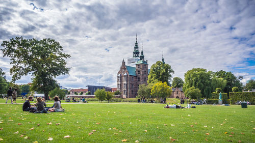 People on lawn against built structures