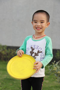 Cheerful boy holding plastic disc at park