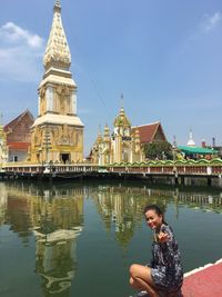 Portrait of woman showing tortoise by lake against temple