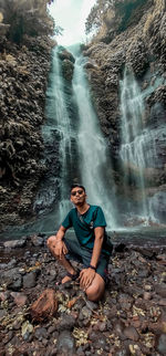 Full length portrait of young man standing on rock