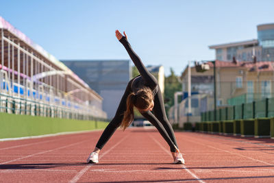 Full length of woman exercising on running track