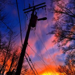 Low angle view of silhouette electricity pylon against sky during sunset