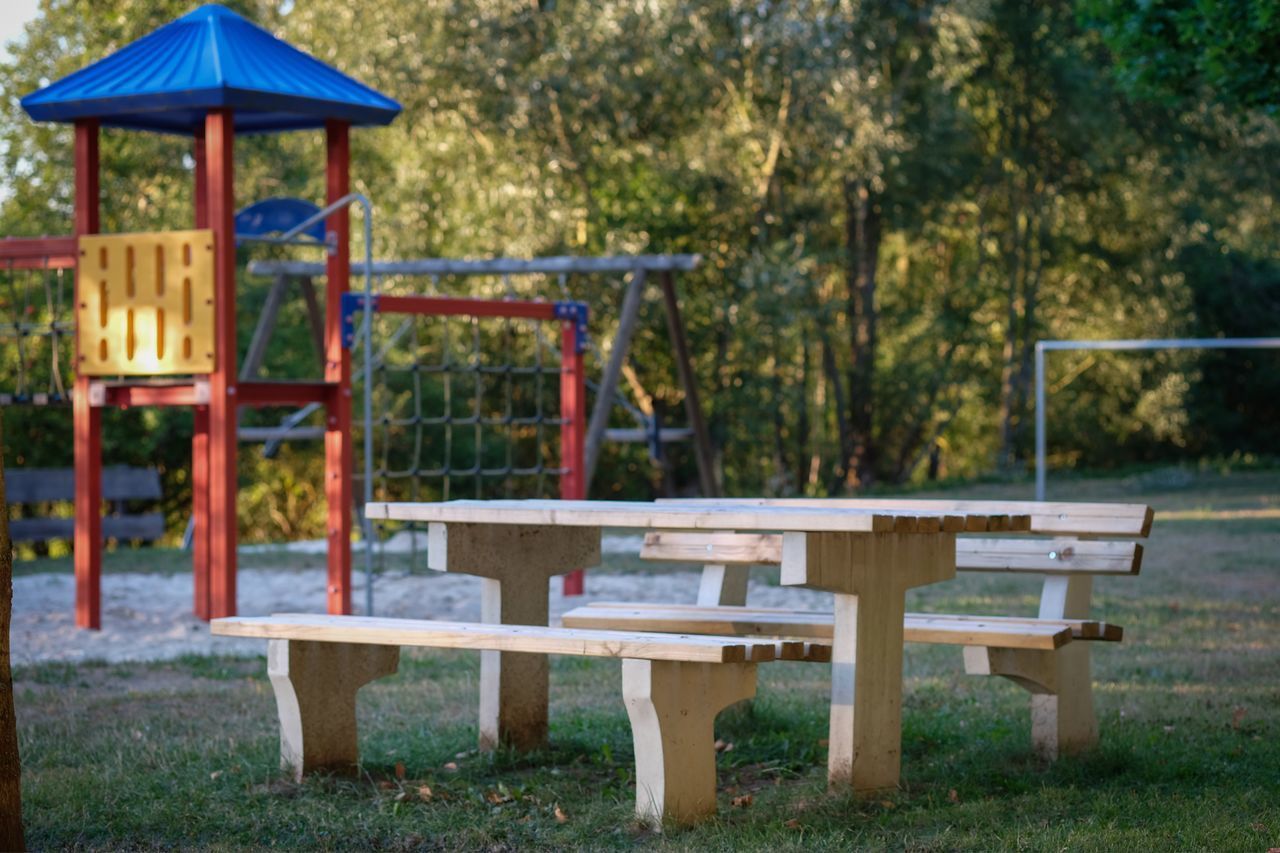 EMPTY PARK BENCH ON FIELD