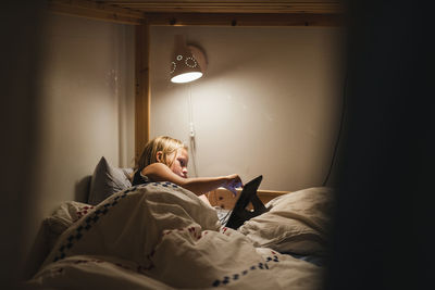 Girl using digital tablet on bed