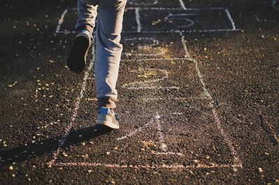 Low section of person playing hopscotch on street